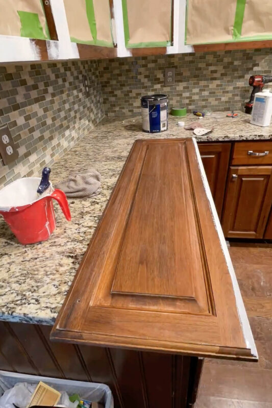 Prepping cabinet doors for painting by sanding and brushing the edges. 